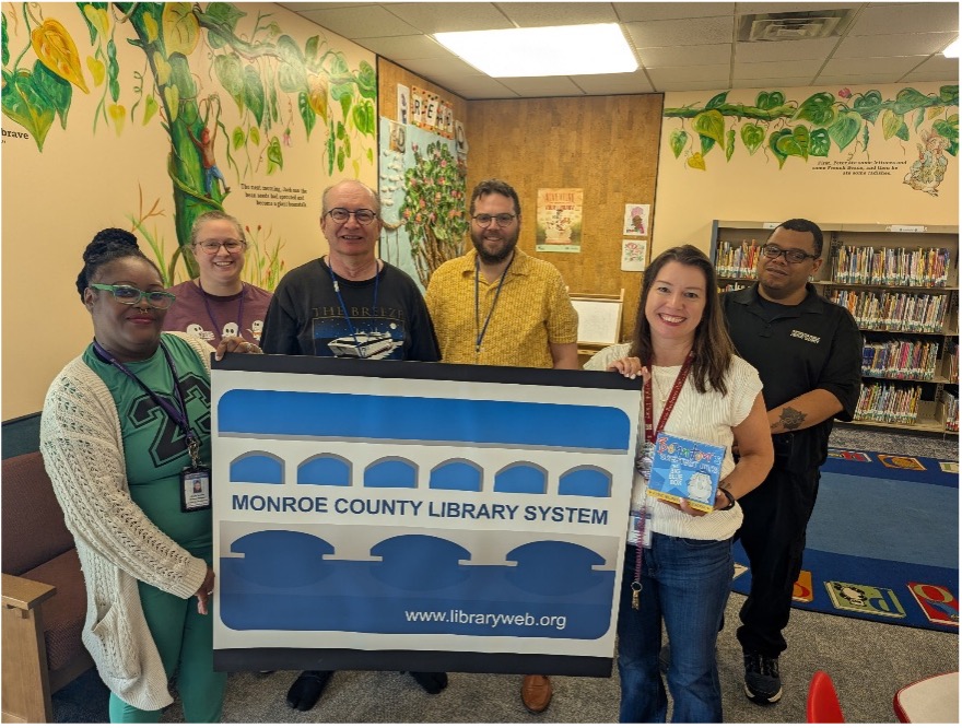 photo of Library raffle winner with staff and large poster of a library card